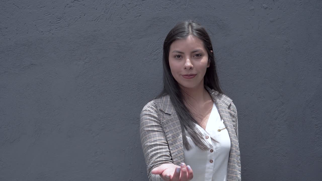 una niña latina sonriente hace un gesto de llamada con sus dedos, transmitiendo alegría y amabilidad en un gesto amigable y cálido