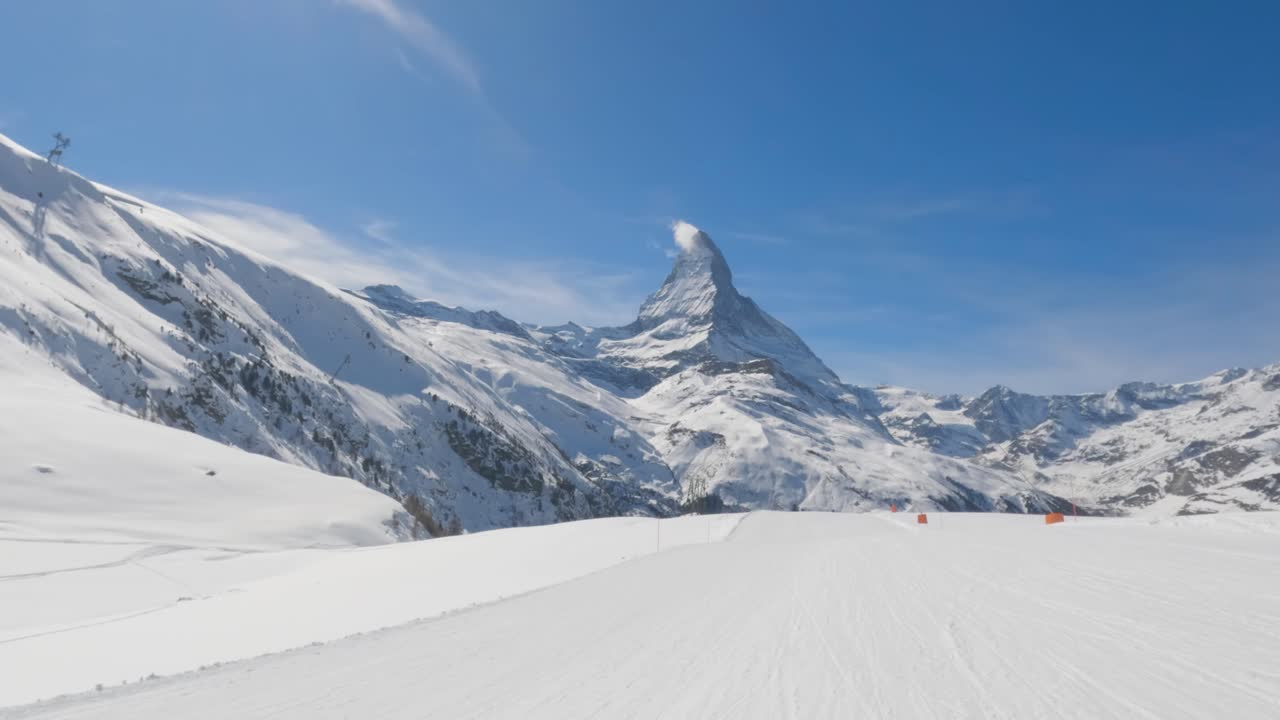 vista en primera persona de esquiar cuesta abajo en una pista de esquí vacía con el pico de la montaña matterhorn en el fondo