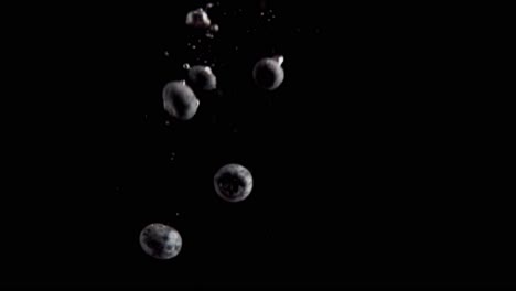 currants falling into water super slowmotion, black background, lots of air bubbles, 4k240fps