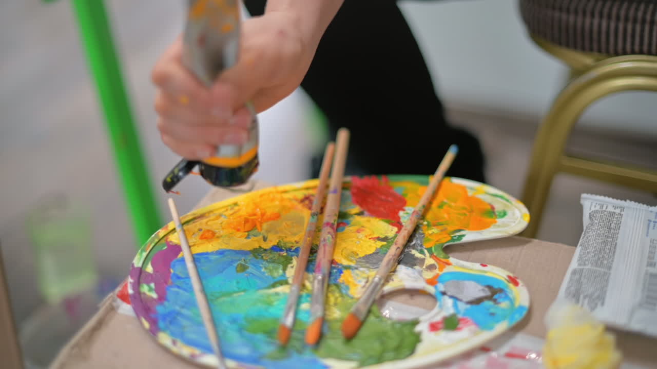 A woman adding yellow paint on a palette in a studio. Slow motion