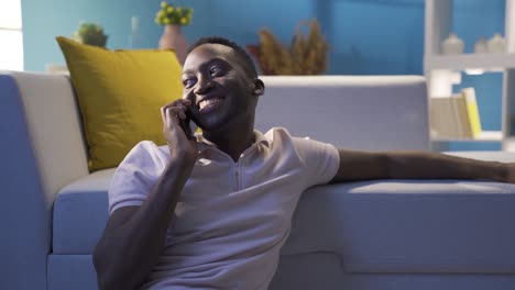black man talking on the phone at night at home with his friend and girlfriend.
