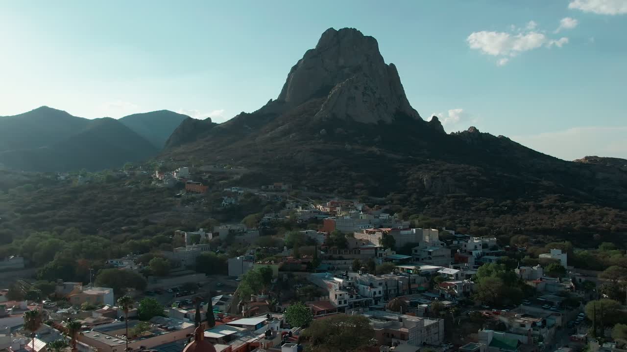 Ripresa aerea all'indietro della Peña de Bernal che rivela il centro città di Bernal, pueblo magico, e il Tempio di San Sebastiano