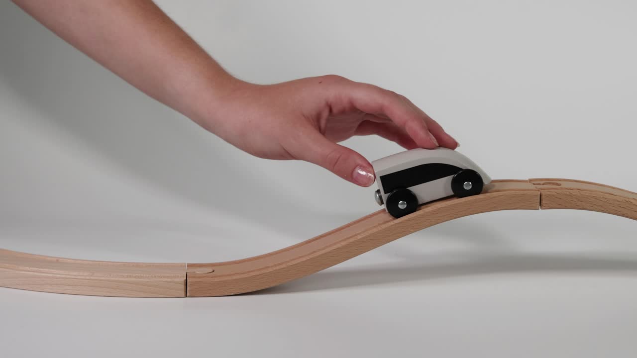 손은 물결 모양의 트랙에서 장난감 차를 움직인다