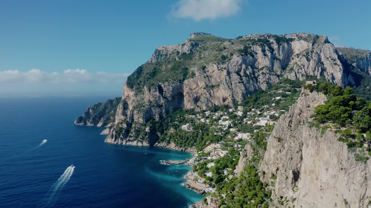 Vista aerea con drone della costa dell'Isola di Capri con scogliere calcaree rocciose, mare Mediterraneo turchese e ville costiere di lusso situate nella Baia di Marina Piccola. Esclusiva destinazione di viaggio in Italia.