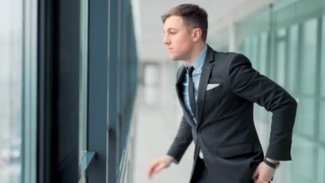 Angry-businessman-standing-by-the-window-in-despair