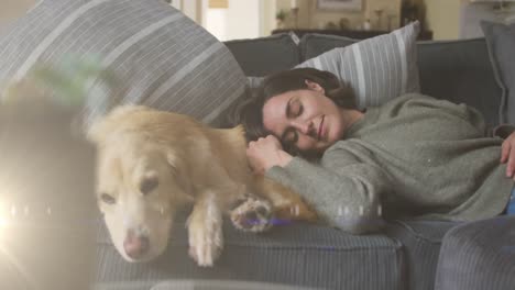 spot of light against caucasian woman sleeping with her dog on the couch at home