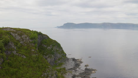 üppig grüner felsiger berg auf der insel vagsoy in der nähe von maloy in norwegen unter dramatischem himmel