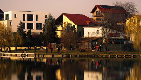 ルーマニアの公共都市公園の風景。夕暮れ時に湖畔を散歩する人々が夕方を楽しんでいる