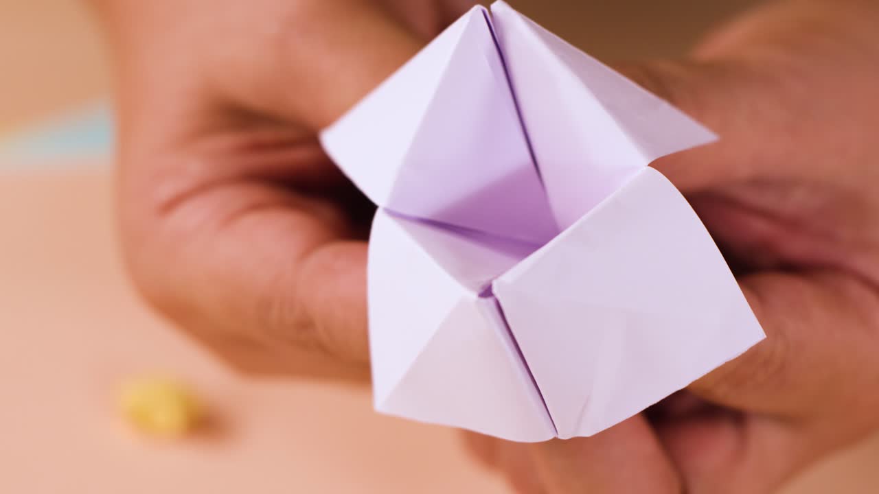 Primo piano di mani che piegano e maneggiano un chiromante di carta bianco su un tavolo
