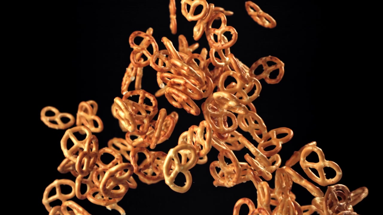 Minipretzels flyver og falder i slowmotion på sort baggrund