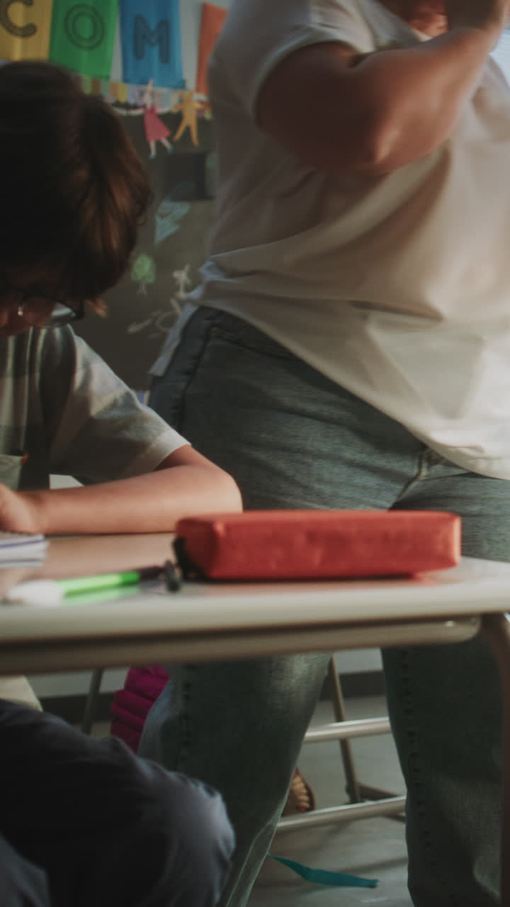 Elementary School Students Sitting at the Desks Writing School Test or Lecture in Notebooks