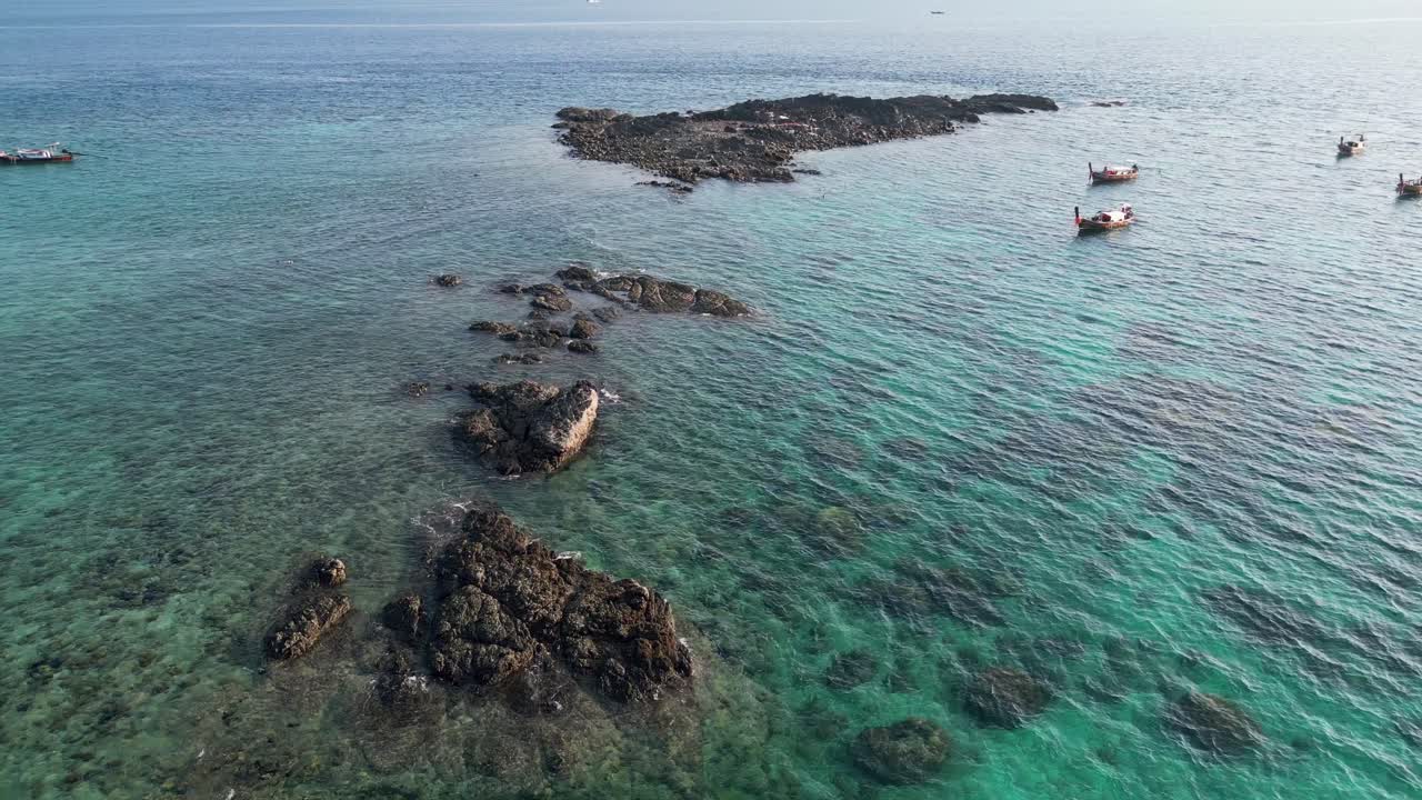 Tranquilla veduta aerea di Blacktip Reef Shark Point vicino a Phi Phi, con acqua turchese cristallina, affioramenti rocciosi e tradizionali barche longtail thailandesi