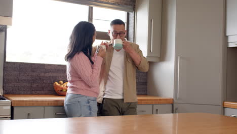 asian couple enjoying coffee together in cozy kitchen, sharing warm conversation