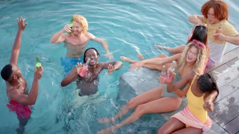 happy diverse friends with drinks dancing and swimming in pool in slow motion