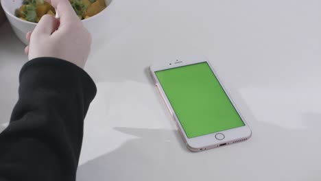 personas comiendo almuerzo mientras usan un teléfono inteligente de pantalla verde