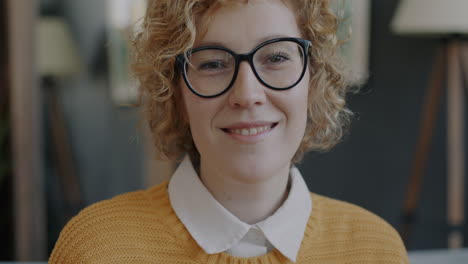 mujer sonriente con cabello rizado y gafas