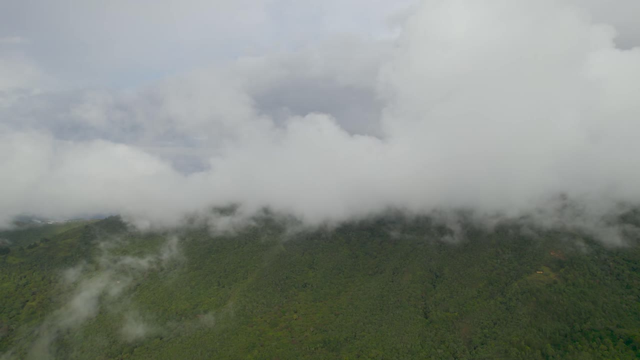 Dolly inn slowly with drone over mountains with view of clouds at a foggy morning in Colombia