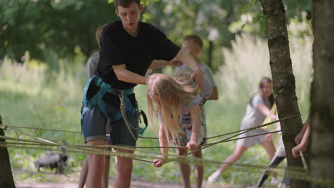 en el campamento de verano mi hija aprende a superar obstáculos de cuerda y escalada en roca. enseñar a los niños sobre turismo y senderismo