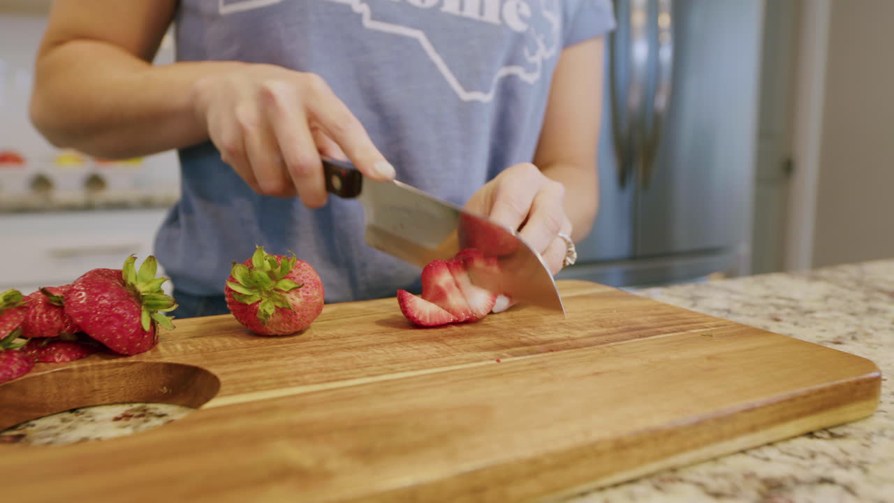 mujer cortando fresas frescas en una tabla de cortar