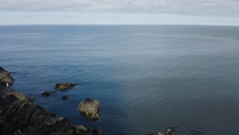 Drone-is-flying-towards-the-sea-along-the-rocky-shore-of-Clogherhead,-Ireland-1