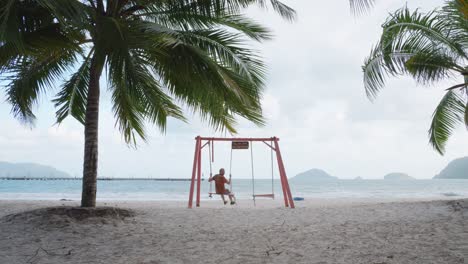 Lone-Man-Swinging-On-The-Seacoast-Of-Bai-Tam-An-Hai-Beach-In-Con-Dao-Island,-Vietnam