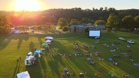 Der-Sonnenuntergang-Erhellt-Den-Park-Mit-Menschen,-Die-Soziale-Distanz-üben,-Um-Filme-Anzusehen