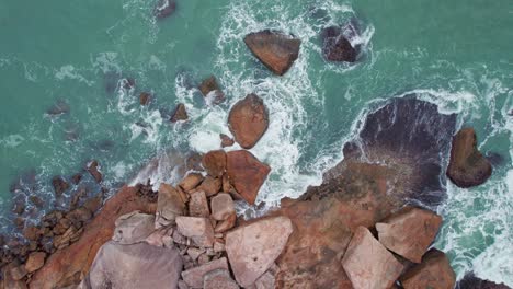 Aerial-view-of-the-sea-waves-on-the-rocks-positioned-along-the-sea-shore