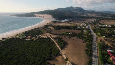 Wide-aerial-view-of-the-ocean,-rural-farmland,-and-main-highway-in-Tarifa,-Spain