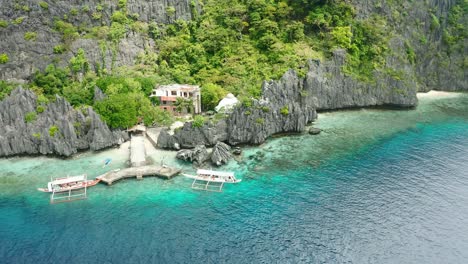 beautiful mantiloc shrine resort hidden behind giant gray rocks and green trees with an amazing view on the clear blue ocean at mantiloc island near el nido in the philippines