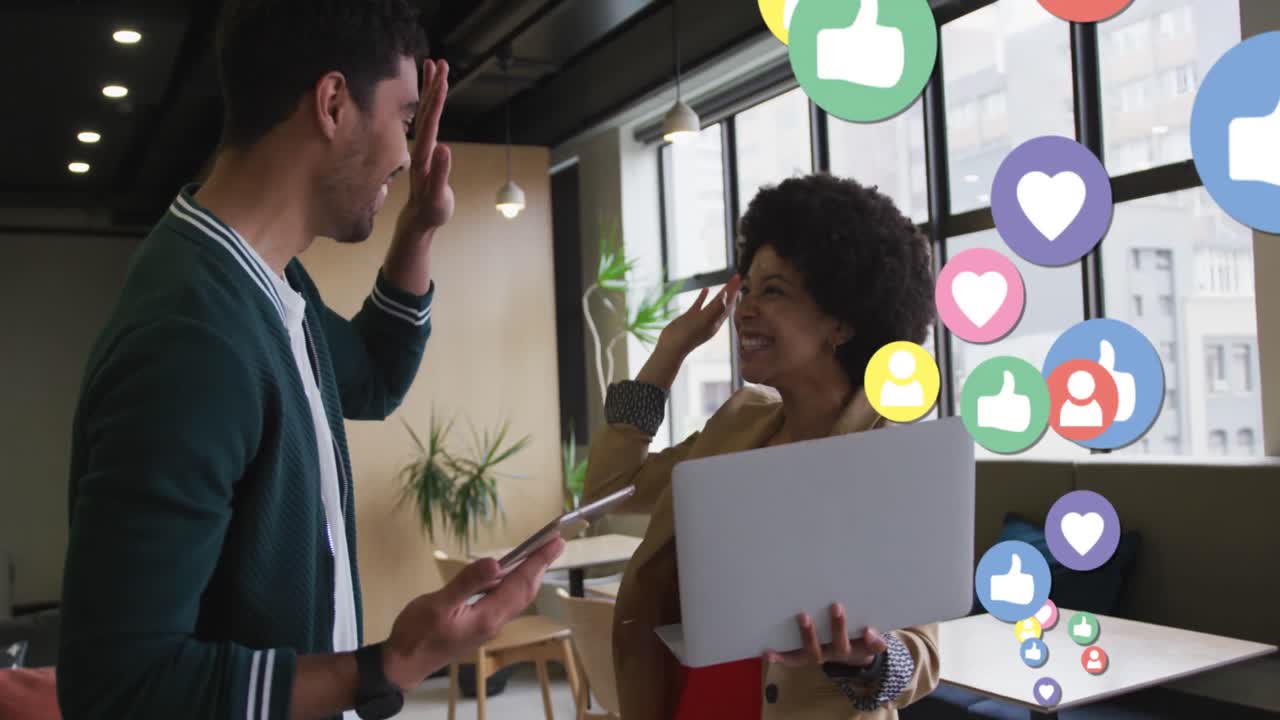 Animation of media icons over diverse business people smiling and using laptop