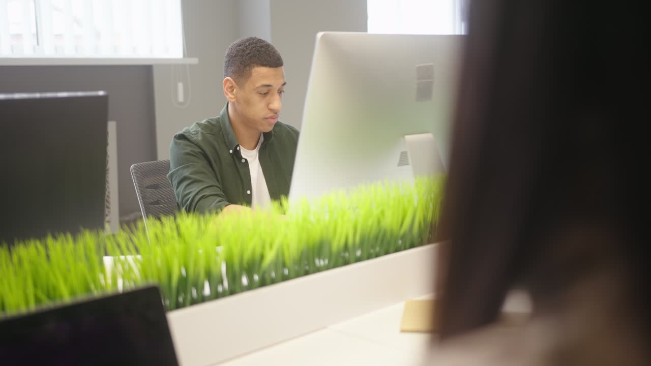 Multinational people sit at desks working on computers