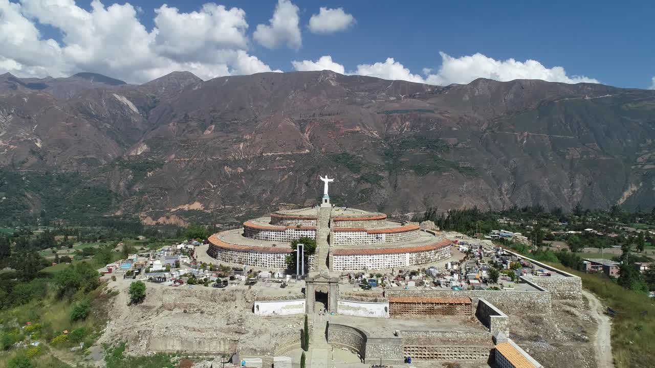 A breathtaking aerial shot of a tiered cemetery crowned by a Christ statue, set against the rugged Andes. Perfect for travel, history, and cultural imagery