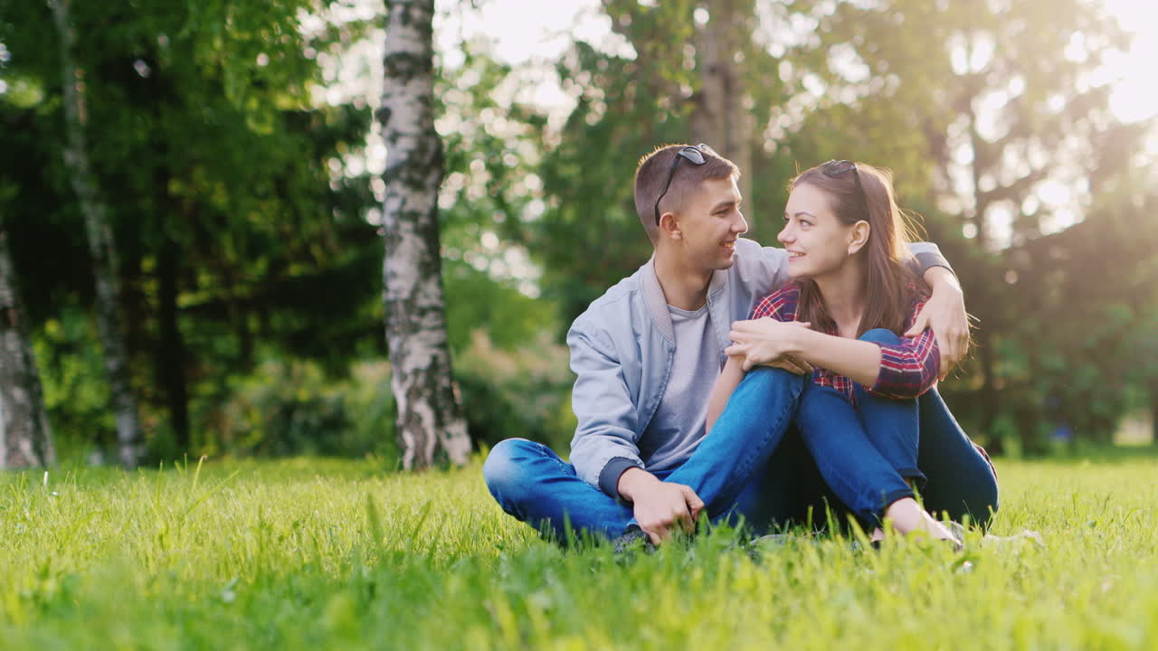 태양이 아름다운 반사를 빛나고 웃는 포옹 공원에서 편안한 젊은 매력적인 부부