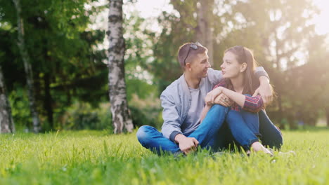 joven pareja atractiva relajándose en el parque abrazándose sonriendo el sol brilla hermoso reflejo