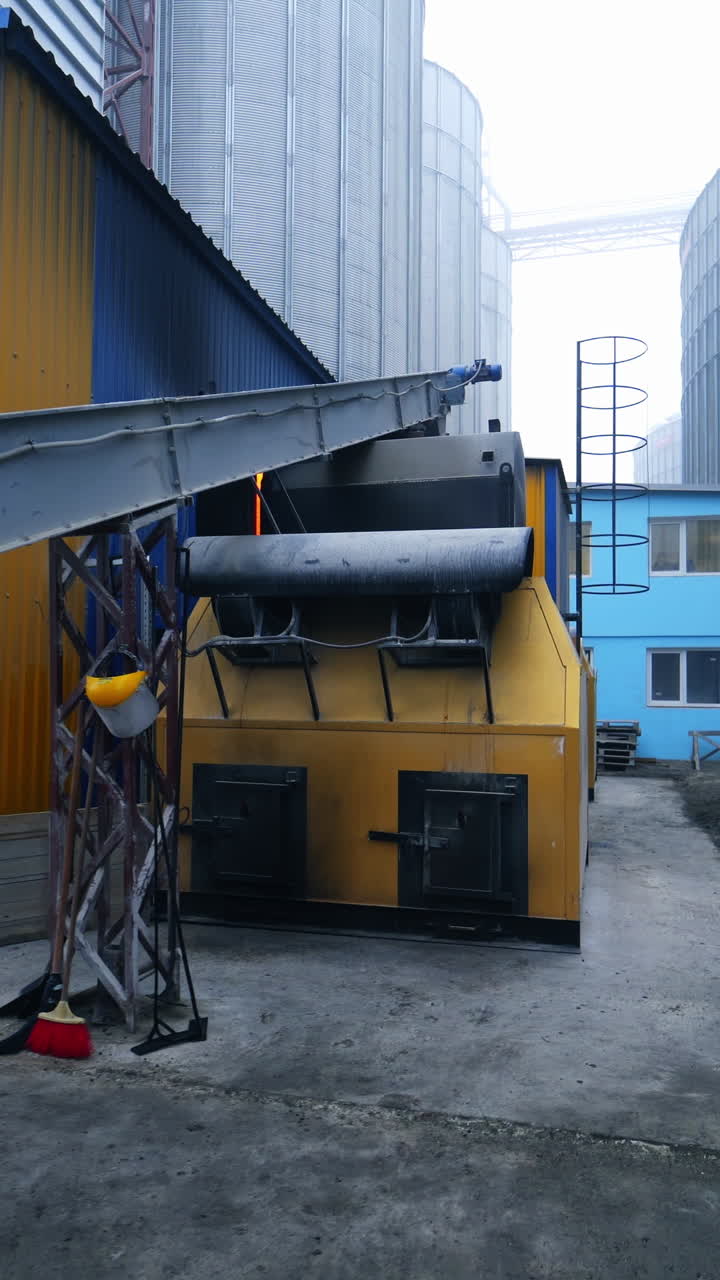 Exterior of the elevator furnace premises with a long orthogonal tube. View of the exterior with gradual distancing. Huge tanks at the backdrop. Vertical video