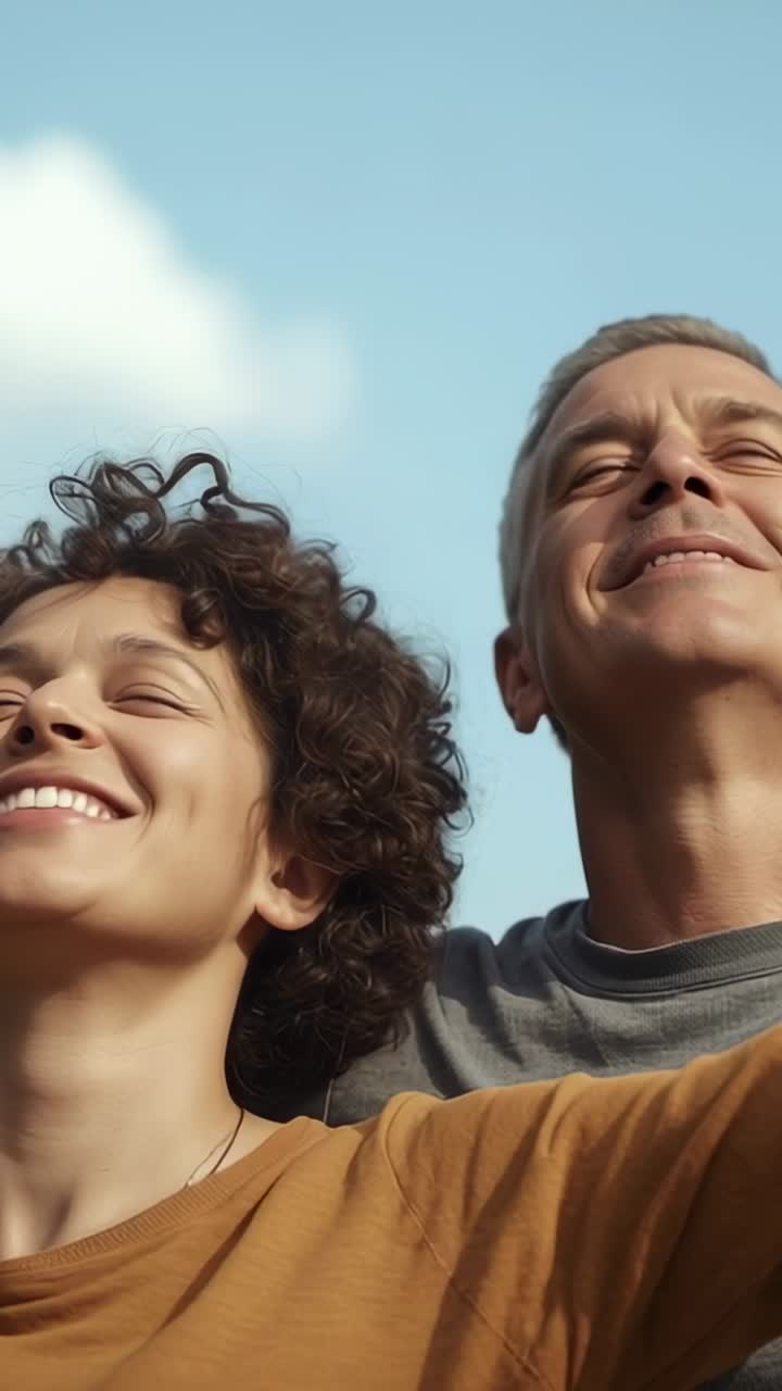 Vídeo vertical: casal sorrindo aproveitando o sol, se inclinando em um parque, usando blusa mostarda, camiseta cinza e colar