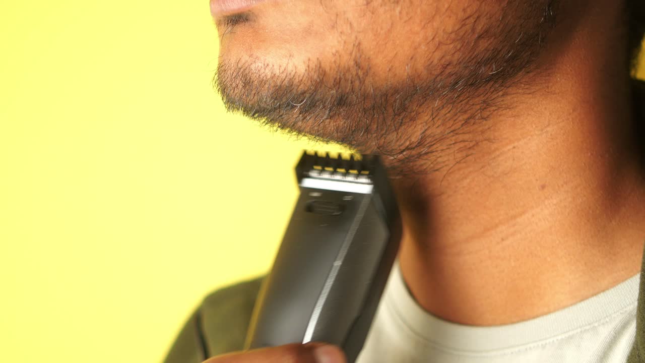 hombre recortando su barba con una navaja eléctrica