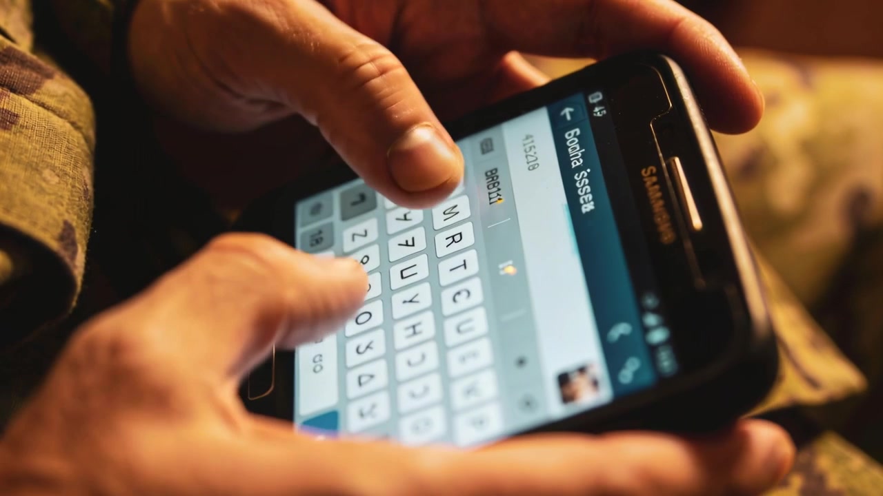 Seeing contact Scoda Sss, man's hands typing message on smartphone keyboard in shelter, camouflage
