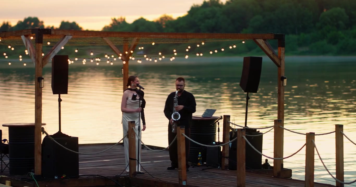Musicisti che si esibiscono su un pontile galleggiante al tramonto