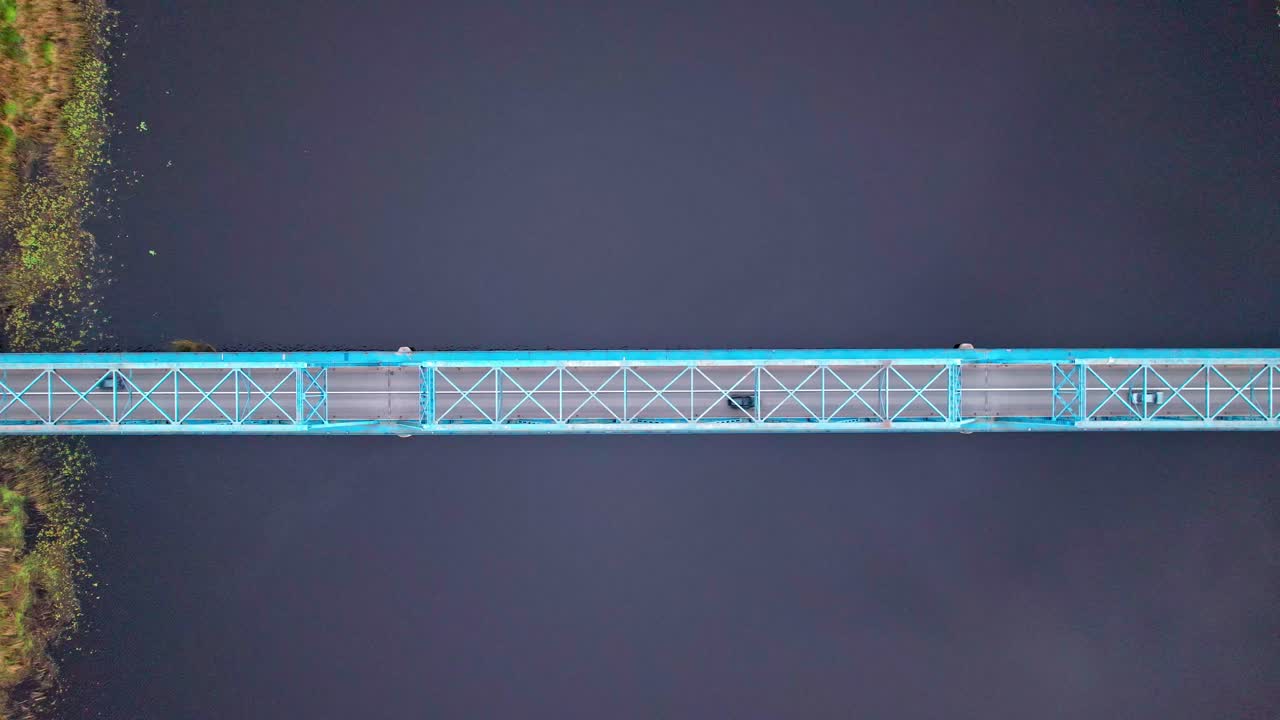 View of blue bridge over dark water in Latvia from above