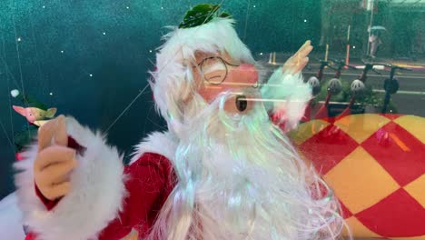 santa claus en el escaparate siendo colocado por alambre con duendes de mercadería de vidrio