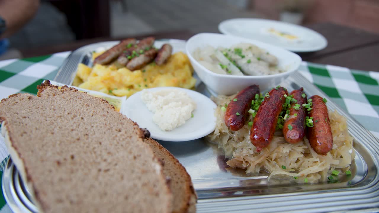 Close-up of German sausages, sauerkraut, potato salad, rye bread, and horseradish on outdoor table