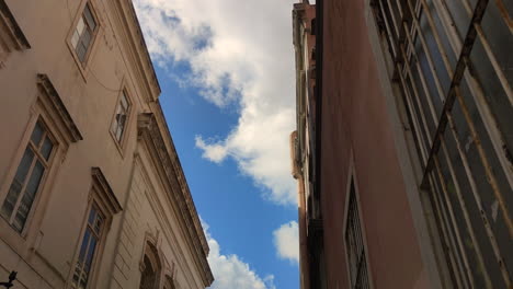 blue sky with white clouds between old buildings - low angle, timelapse