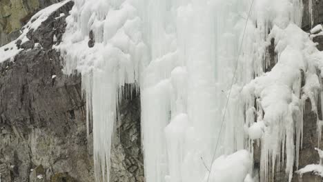 climber on ledge assisting fellow climber scale ice cascade ascending aerial 4k