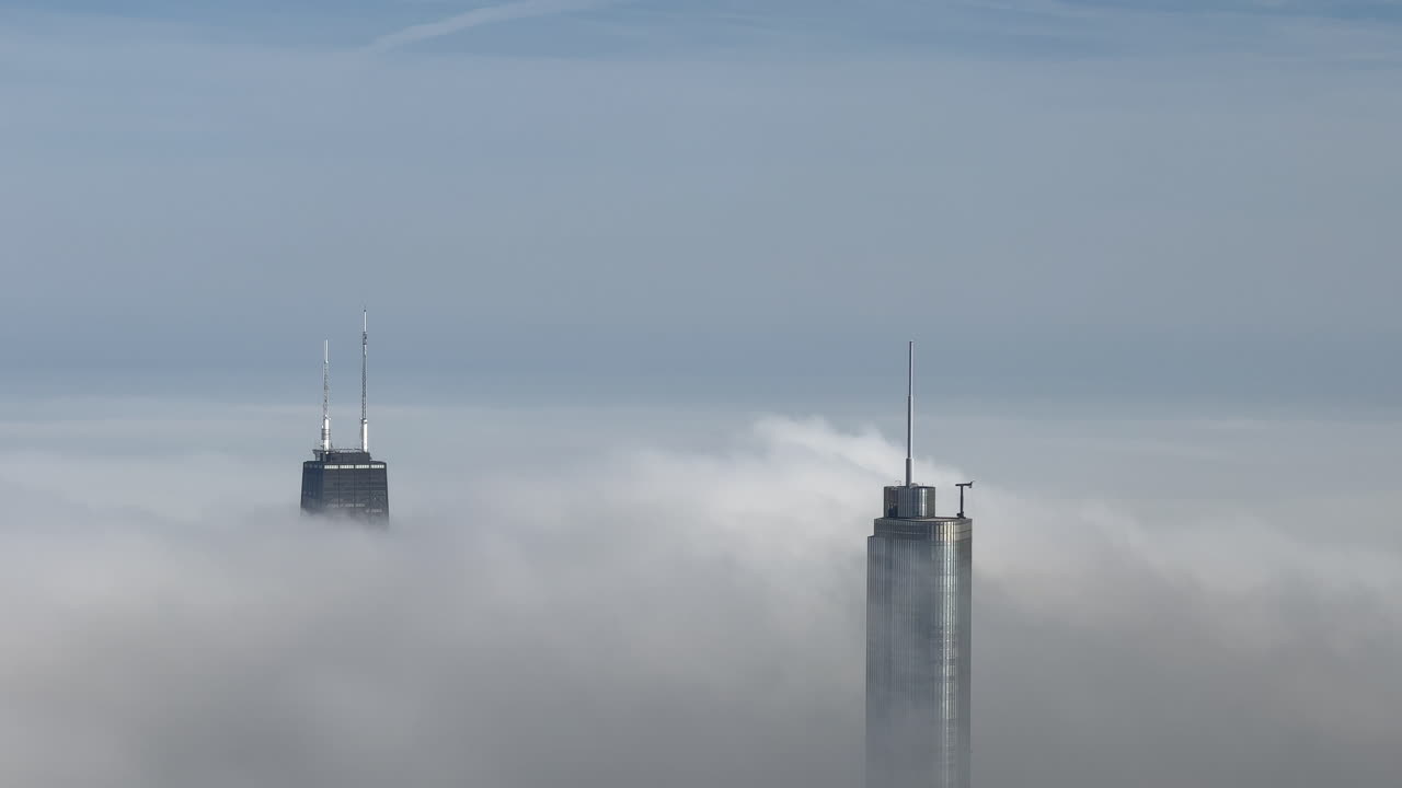 dos rascacielos de chicago que sobresalen por encima de las nubes bajas de niebla