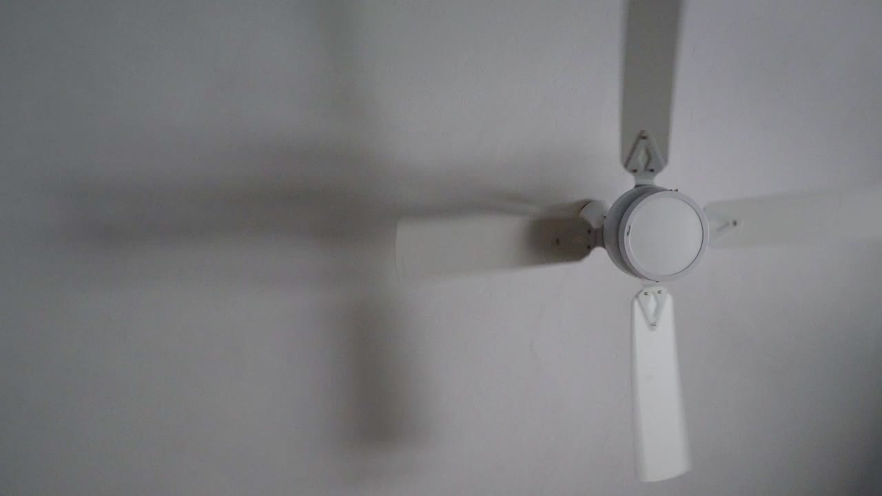 Slow-motion zoom-in view of a white ceiling fan.