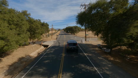 Fpv-drone-view-of-black-pick-up-driving-fast-on-road