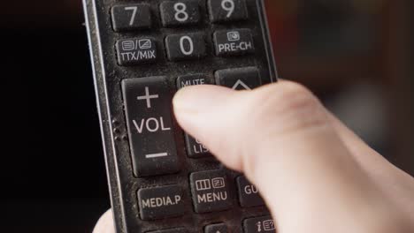 setting pressing volume button up of tv remote control using finger, close up