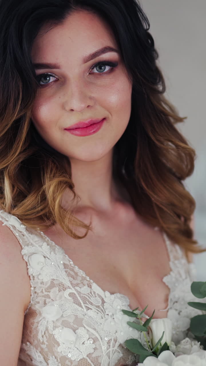 Wedding bouquet of creamy roses in the hands of a beautiful bride. Lovely young woman dressed in white wedding dress is holding flowers. Close-up. Vertical video