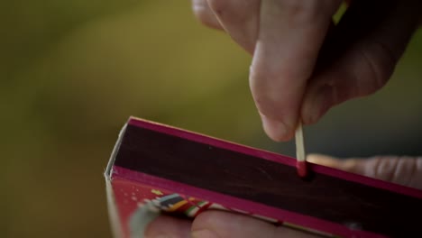 close up of unidentified hand striking matchstick over matchbox to ignite it